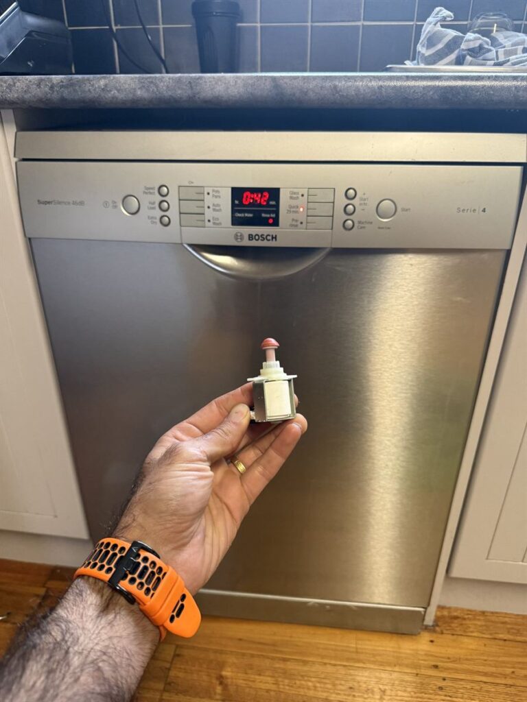 Technician holding the faulty outlet valve removed from the Bosch dishwasher