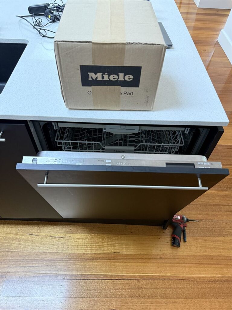 Miele integrated dishwasher opened for repair with a genuine Miele spare part box on the bench